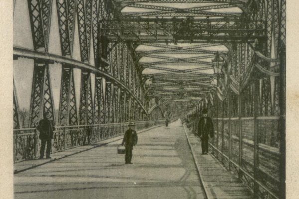 Pozdrowienia z Fordonu. Najdłuższy most w Niemczech o długości 1325 m. Z prawej za ażurowym płotem linia kolejowa. Nawierzchnia mostu drewniana. W środku przęsła widoczna suwnica techniczna, poruszająca się na szynach zamontowanych w połowie konstrukcji.  1902, A. Pohlmann, ze zbiorów Rafaela Prętkiego